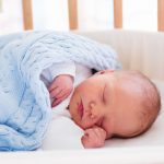 Newborn baby boy in hospital cot